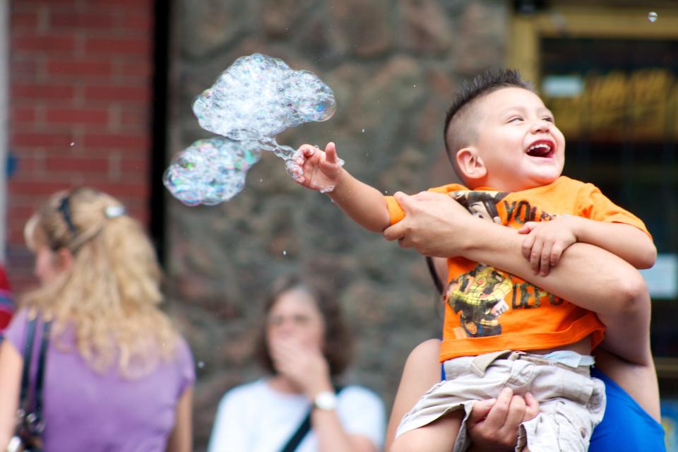 A baby plays with bubbles at a Servicios de la Raza event.