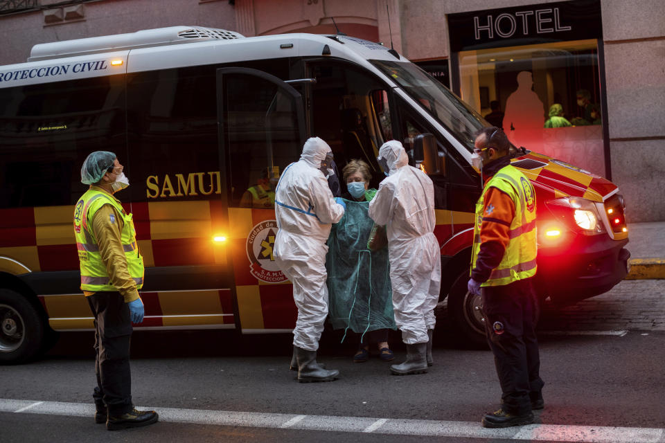 A patient, center, is transferred to a medicalised hotel during the COVID-19 outbreak in Madrid, Spain, Tuesday, March 24, 2020. For most people, the new coronavirus causes only mild or moderate symptoms. For some it can cause a more serious illness. (AP Photo/Bernat Armangue)