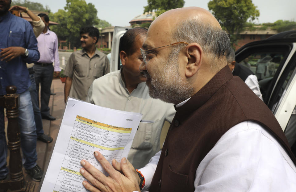 FILE - In this Monday, Aug. 5, 2019, file photo, Indian Home Minister Amit Shah arrives at the Parliament carrying a copy of a confidential document that lists out the procedure for revoking Kashmir's special status in New Delhi, India. Shah says normalcy has returned in most areas in Indian-controlled Kashmir but the detention of politicians and the blockade of the internet and social media are continuing because of security concerns. Asked by lawmakers in Parliament on Wednesday, Nov. 20, how soon the restrictions are likely to be lifted, Shah says authorities have to fix priorities when it comes to security and the fight against terrorism. India stripped the region of its semi-autonomous powers and implemented a strict clampdown on Aug. 5. (AP Photo/Manish Swarup, File)
