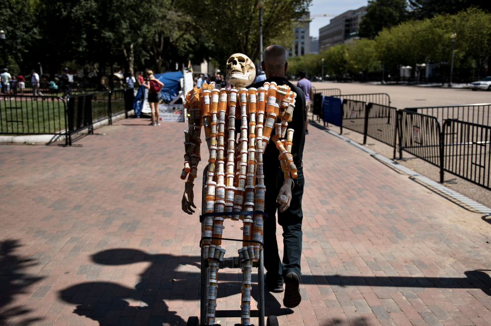 Frank Huntley, who struggled with addiction, walks with Pill Man, a skeleton made from his oxycontin and methadone prescription bottles, along Pennsylvania Avenue August 30, 2019, in Washington, DC. (Photo: BRENDAN SMIALOWSKI/AFP/Getty Images) 