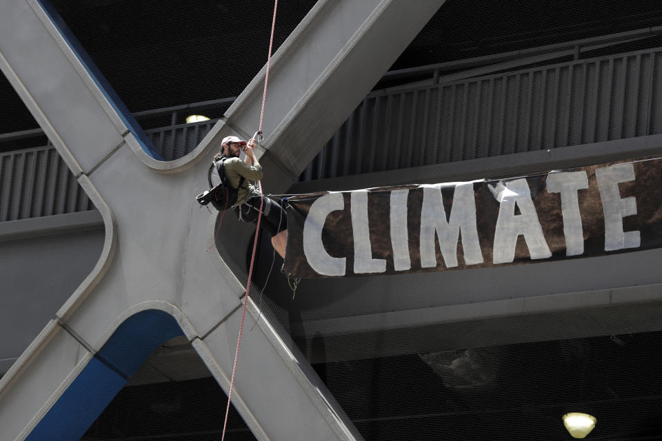 A man rappels down the side of the Port Authority Building with a sign during a climate change rally outside of the New York Times building, Saturday, June 22, 2019, in New York. Activists blocked traffic along 8th Avenue during a sit-in to demand coverage of climate change by the newspaper. (AP Photo/Julio Cortez)