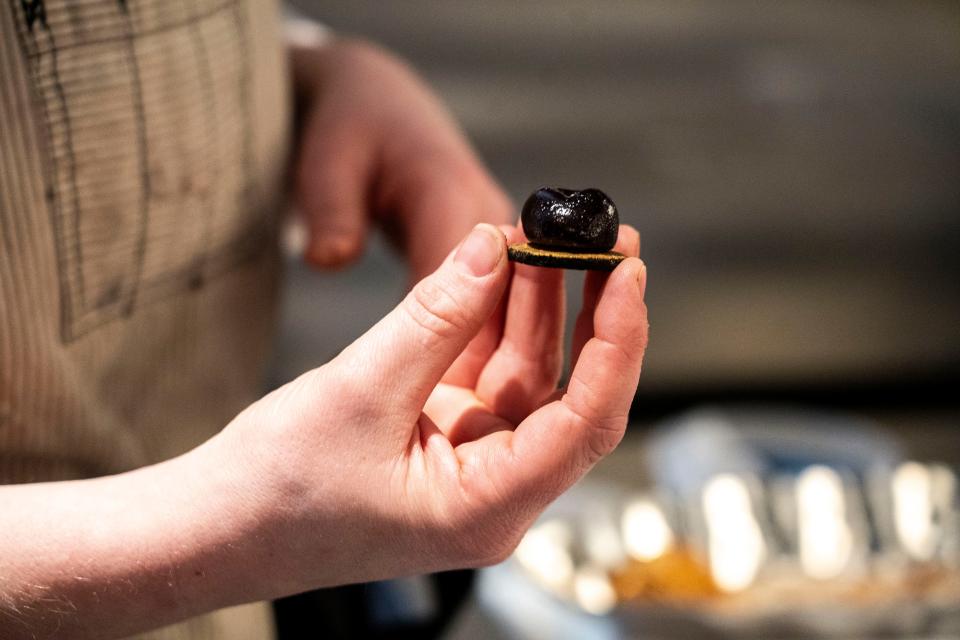 Oak Park executive pastry chef Jess Robertson holds a cherry pate de fruit that’s like a homemade gummy shaped like a cherry and dipped in chocolate at Oak Park on Wednesday, Dec. 20, 2023, in Des Moines.