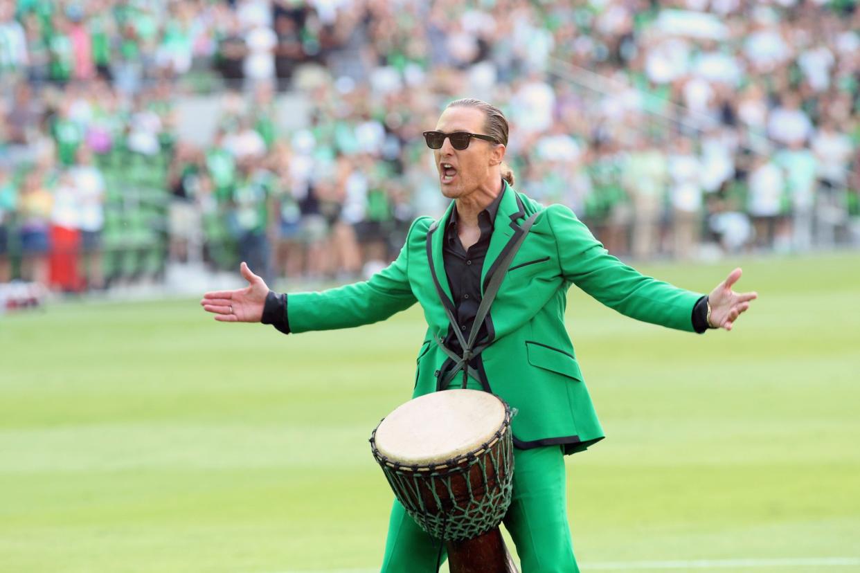 Matthew McConaughey in a green suit with a drum between his legs
