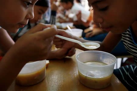 Students enjoy the soup cooked for them during an activity for the end of the school year at the Padre Jose Maria Velaz school in Caracas, Venezuela July 12, 2016. REUTERS/Carlos Jasso