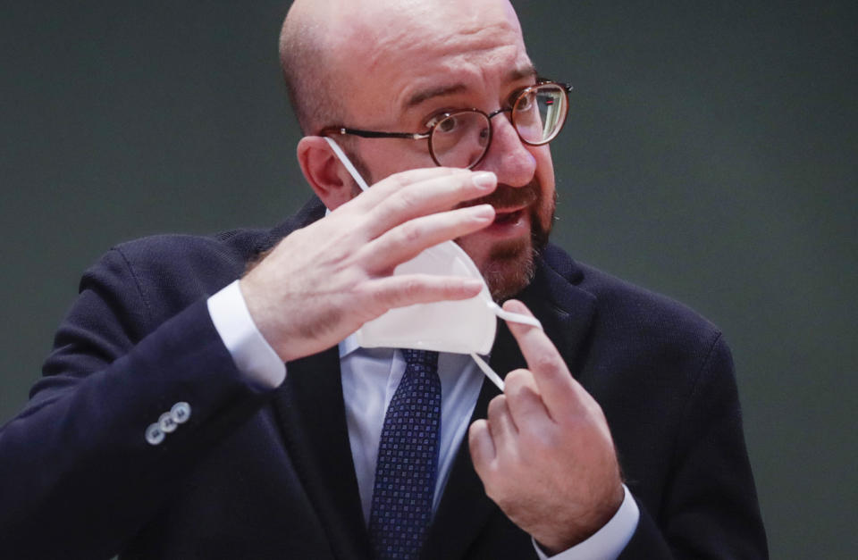 European Council President Charles Michel takes off his protective face mask as he prepares to take part in an EU Summit, via videoconference link, at the European Council building in Brussels, Thursday, Feb. 25, 2021. European Union leaders are gathering Thursday, via videoconference link, to try to inject new energy into the 27-nation bloc's lagging coronavirus vaccination effort as concern mounts that new variants might spread faster than authorities can adapt. (Olivier Hoslet, Pool via AP)