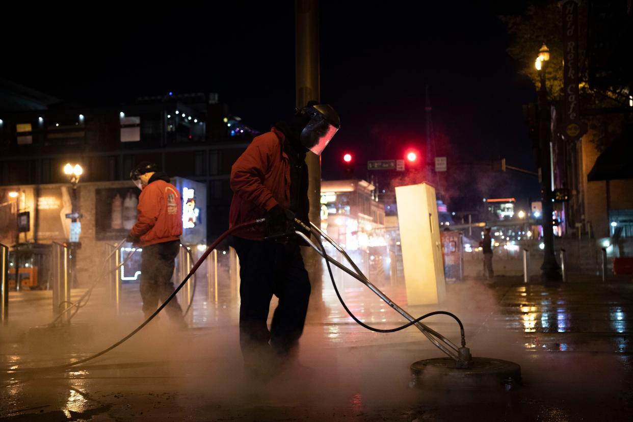 Deone Fields cleans the sidewalks before dawn, downtown Nashville, Tenn., Monday, Nov. 13, 2023.