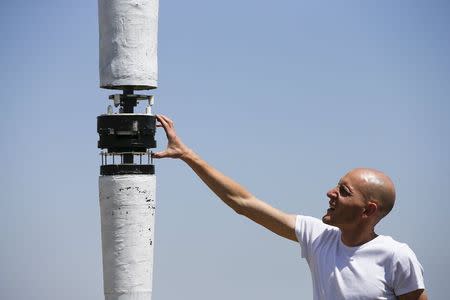 David Yanez touches the alternator of a 6-metre (20-ft.) prototype of a wind turbine without blades in a countryside at the small village in Gotarrendura, Spain, June 2, 2015. REUTERS/Sergio Perez