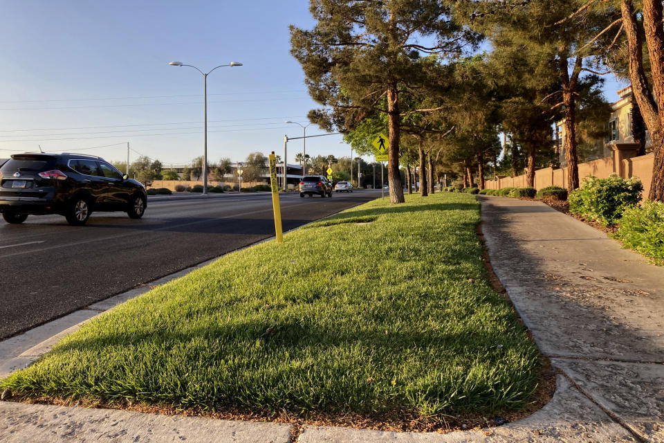 FILE - Traffic passes a grassy landscape on Green Valley Parkway in suburban Henderson, Nev., on April 9, 2021. In November 2022, some of the largest water agencies in the western United States agreed to a framework that would dramatically reduce the amount of decorative grass in cities such as Los Angeles, Las Vegas, Salt Lake City and Denver. The agreement comes as the seven states that rely on the overtapped Colorado River are facing a dire future with less water to go around. (AP Photo/Ken Ritter, File)