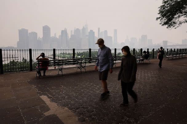 PHOTO: People walk along the Brooklyn Promenade as a reddish haze enshrouds the Manhattan skyline as a result of Canadian wildfires, June 06, 2023 in New York City. (Spencer Platt/Getty Images)