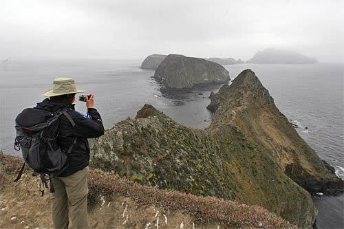 A hiker captures the view for posterity from Inspiration Point on East Anacapa Island. Sixteen miles southwest of Ventura, Anacapa's three volcanic islets rise steeply from the sea. The islets seem to float on the horizon like a distant mirage. The name, in fact, is derived from a Chumash word for “mirage.”