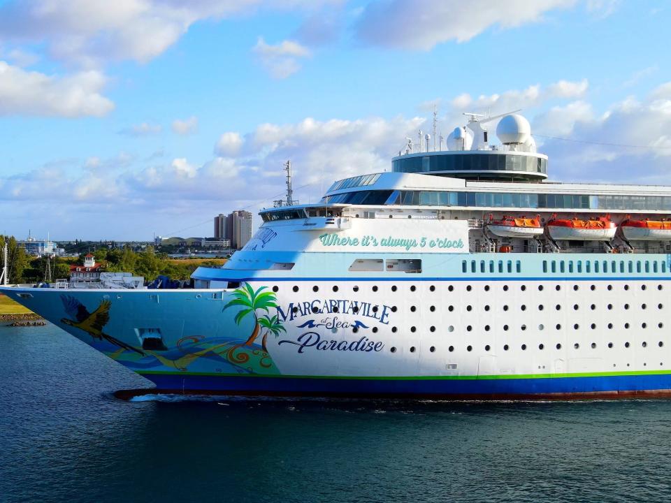 A close up of a Margaritaville branded cruise sailing near land.