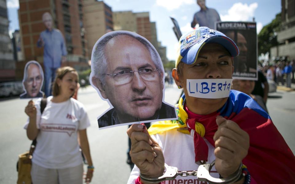 Supporters of arrested Caracas metropolitan mayor Antonio Ledezma hold up a cutout of his face during a gathering in his support in Caracas, Venezuela - Credit:  REUTERS