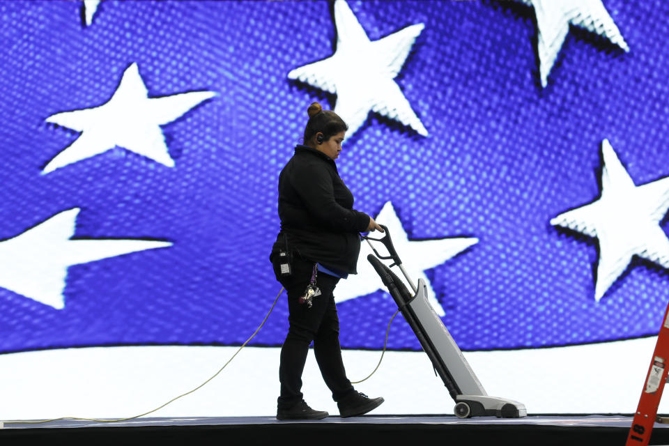 A worker vacuums the stage before the Iowa Democratic Party's Liberty and Justice Celebration, Friday, Nov. 1, 2019, in Des Moines, Iowa. (AP Photo/Charlie Neibergall)