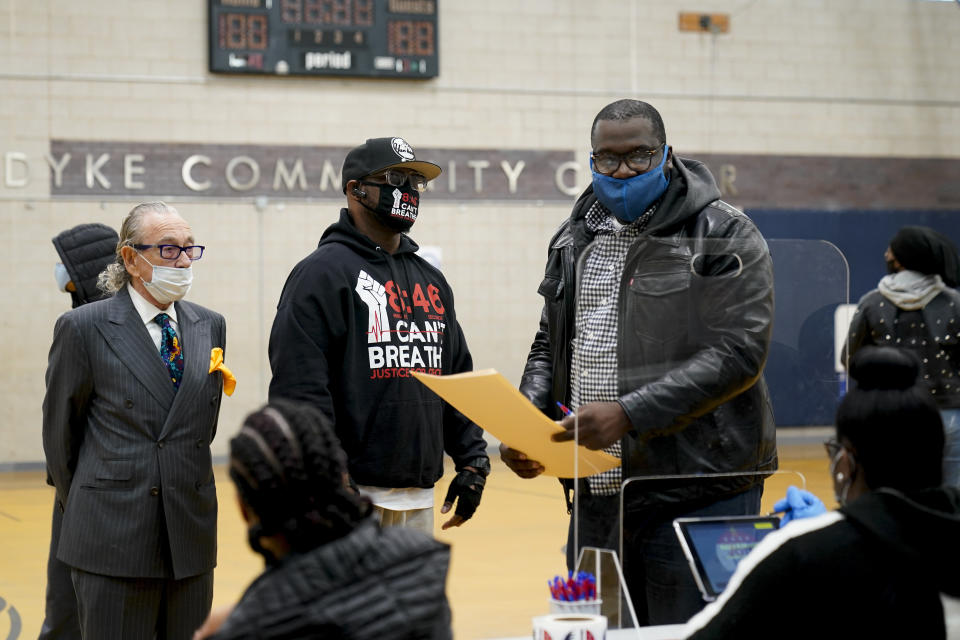 Terrence Floyd, brother of George Floyd, center, waits with Sandy Rubenstein, left, as Rev. Kevin McCall picks up his ballot to vote, Tuesday, Nov. 3, 2020, in the Brooklyn borough of New York. (AP Photo/Frank Franklin II)