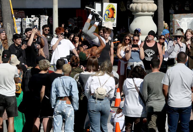 Los Angeles, CA - April 06: The highly contagious norovirus, sometimes referred to as the stomach flu, is on the rise in California, prompting state health officials to urge healthcare providers to step up disinfection efforts in a bid to check the spread. Above, visitors to Venice Beach watch a performer on Thursday, April 6, 2023. (Luis Sinco / Los Angeles Times)