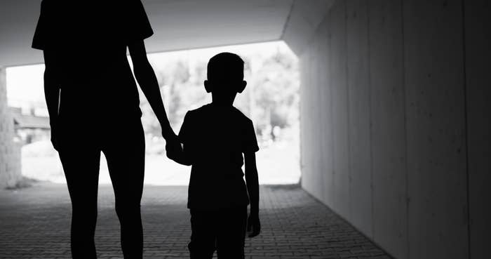 A silhouette of an adult holding hands with a child, walking through a tunnel