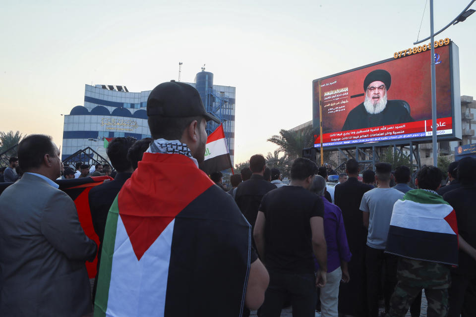 Iraqi demonstrators watch a speech from Lebanon's militant Hezbollah leader Sayyed Hassan Nasrallah on a screen as they hold flags of, Palestinians during a pro-Palestinian rally in Basra, Iraq, Friday, Nov. 3, 2023. (AP Photo/Nabil al-Jurani)