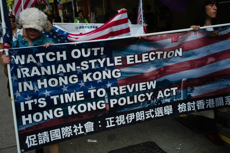 Activists holding a banner and US flags march during a rally against the banning of pro-independence candidates in the upcoming legislative council elections, in Hong Kong, on August 21, 2016