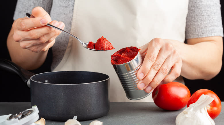 Scooping tomato paste from a can