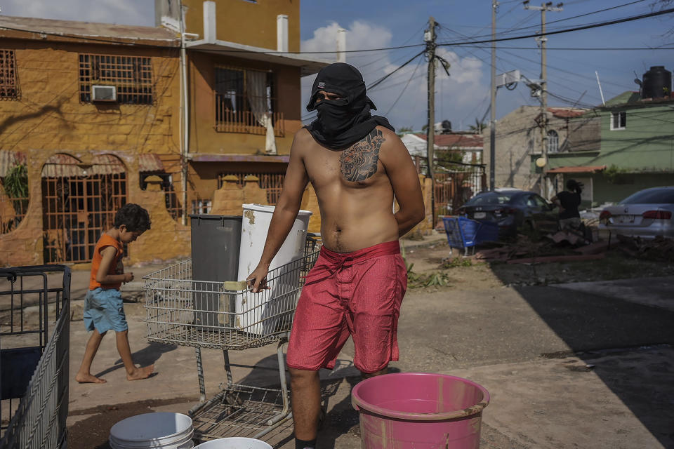 A resident hiding his face with a shirt waits his turn to collect water from a public well in the aftermath of Hurricane Otis in Acapulco, Mexico, Friday, Oct. 27, 2023. Hundreds of thousands of people's lives were torn apart when the fastest intensifying hurricane on record in the Eastern Pacific shredded the coastal city of 1 million. (AP Photo/Felix Marquez)