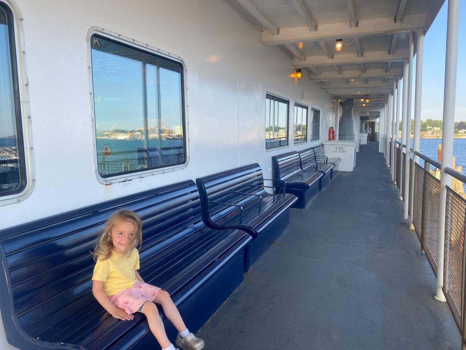 child sitting on a bench on the deck of a ferry
