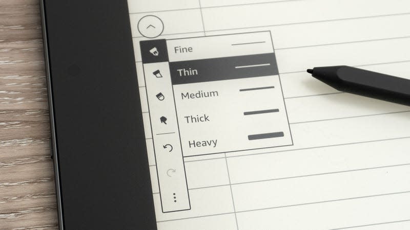 A close-up of the on-screen stroke settings for the Kindle Scribe's stylus, sitting on a wooden desk.