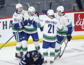 Vancouver Canucks' Oliver Ekman-Larsson (23), J.T. Miller (9), Nils Hoglander (21) and Luke Schenn (2) celebrate Miller's third goal against the Winnipeg Jets, during second-period NHL hockey game action in Winnipeg, Manitoba, Thursday, Jan. 27, 2022. (John Woods/The Canadian Press via AP)