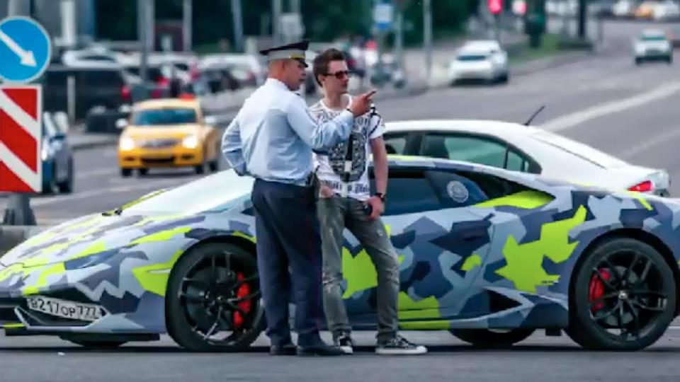 Yakubets speaking with a police officer next to his Lamborghini Huracan.