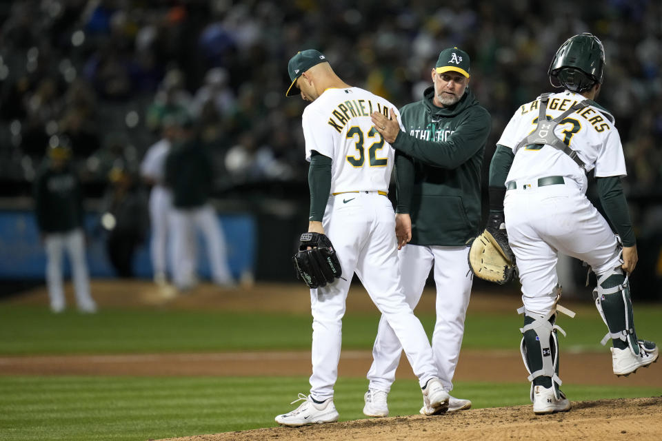 Oakland Athletics pitcher James Kaprielian (32) walks past manager Mark Kotsay, center, after being removed during the fourth inning of the team's baseball game against the New York Mets in Oakland, Calif., Friday, April 14, 2023. (AP Photo/Godofredo A. Vásquez)