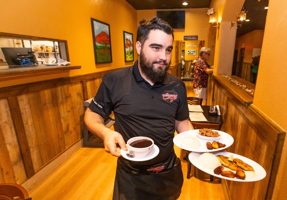 Server Michael Rojas delivers black beans, sweet plantains, rice and pulled pork to patrons on Friday, March 22, at NE Ocala's Latin American Cafe.