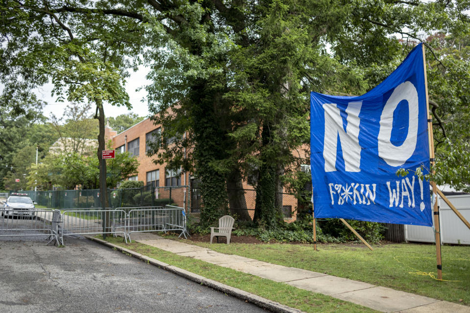 A protest sign stands on the lawn of Scott Herkert beside the former Saint John Villa Academy that has been repurposed as a shelter for homeless migrants, Wednesday, Sept. 13, 2023, in the Staten Island borough of New York. Herkert, a New Yorker upset that the city has been housing homeless migrants on his suburban block, has set up a loudspeaker to deliver an unwelcoming message in six languages to his new neighbors: "The community wants you to go back to New York City. Immigrants are not safe here." (AP Photo/John Minchillo)