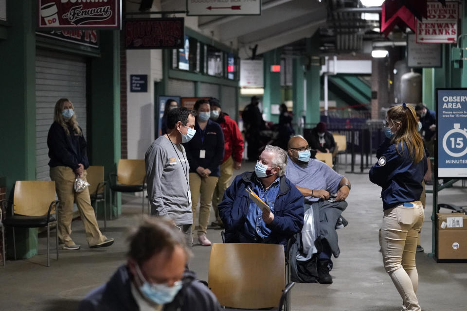 FILE - In this Jan. 28, 2021, file photo, Boston Marathon Race Director Dave McGillivray, second from left, oversees a COVID-19 vaccine injection site staged in a concession area at Fenway Park in Boston. More than 1 million COVID-19 vaccination shots have been given at Major League Baseball stadiums, with the Oakland Coliseum and Marlins Park among the sites planning to continue operating after opening day. The 11 ballparks that converted to mass vaccination centers in the offseason combined to pass a million total shots this week, MLB said Friday, March 25. (AP Photo/Charles Krupa, File)