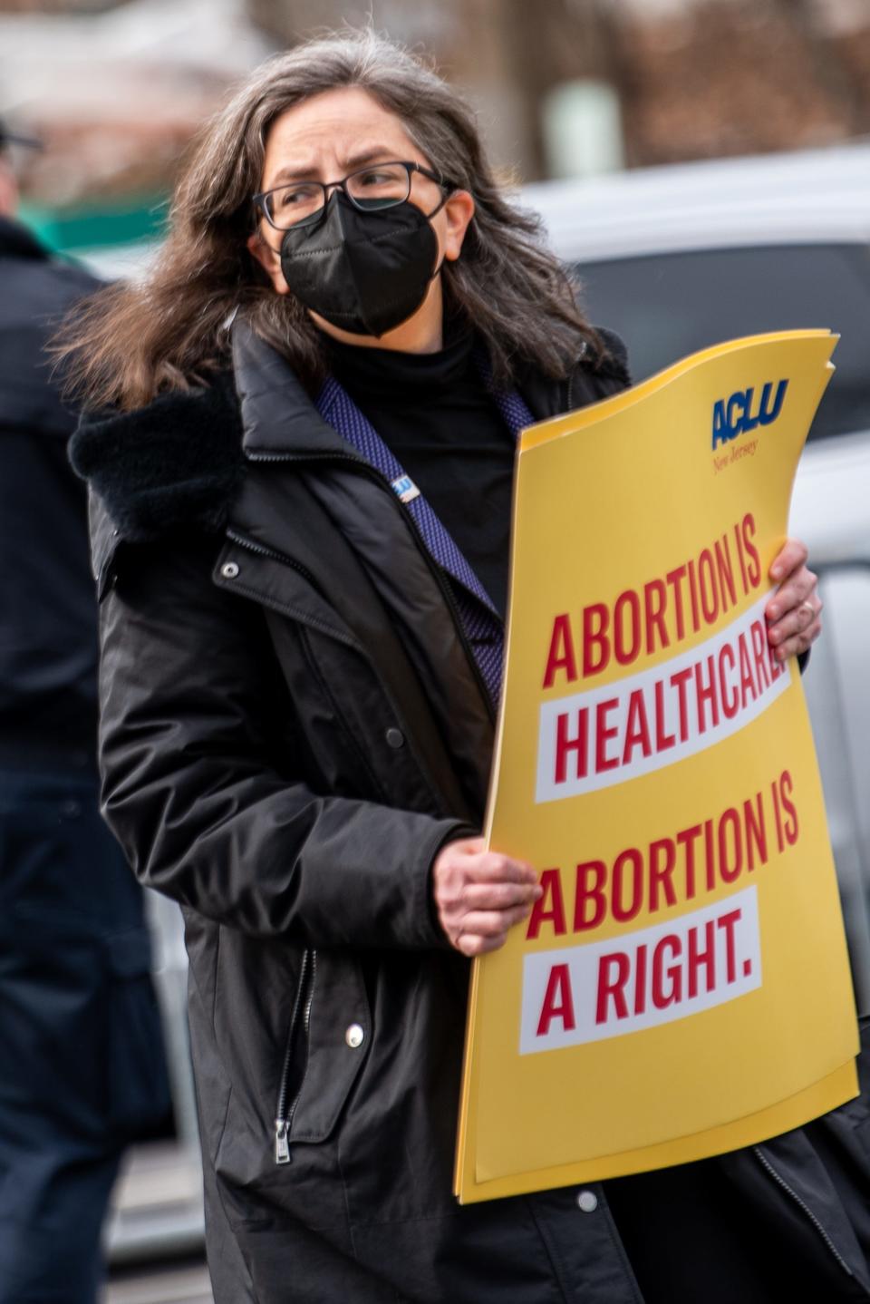 New Jersey Gov. Phil Murphy signs an abortion bill into law in front of Teaneck Library on Thursday Jan. 13, 2022. Jeanne LoCicero with the New Jersey ACLU carries signs during the bill signing ceremony. 