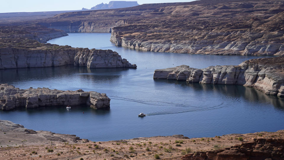 FILE - In this Saturday, July 31, 2021 file photo, a boat cruises along Lake Powell near Page, Ariz. This summer, the water levels hit a historic low amid a climate change-fueled megadrought engulfing the U.S. West. Severe drought across the West drained reservoirs this year, slashing hydropower production and further stressing the region’s power grids. And as extreme weather becomes more common with climate change, grid operators are adapting to swings in hydropower generation.(AP Photo/Rick Bowmer)