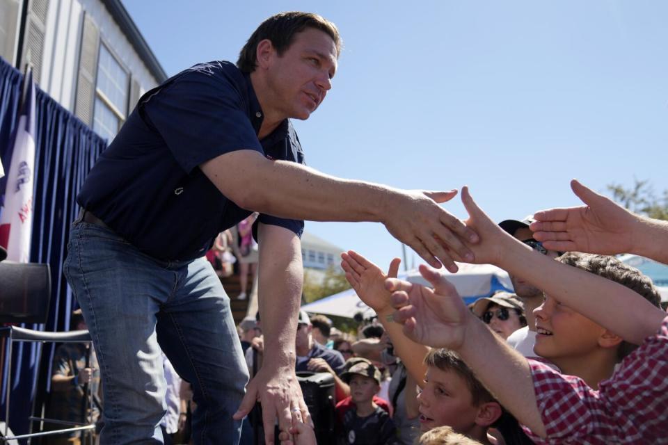 Florida Gov. Ron DeSantis reaches down to shake hands with fairgoers