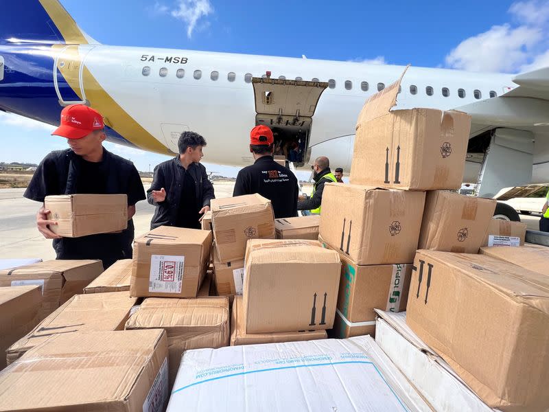 Members of Libya's Youth Hostels Association unload medical aid that arrived by plane at al Abraq airport