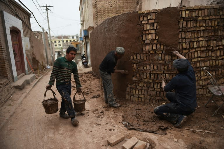 Much of the old city of Kashgar has been redeveloped while local builders have been told to use modern bricks, putting artisan brickmakers out of business and leaving fewer old houses to work on TO GO WITH:China-Xinjiang-unrest-fashion-politics-culture-economy, FEATURE by Benjamin HAAS This photo taken on April 19, 2015 shows workers using modern bricks and mud-based cement to repair a wall in the old city in Kashgar, in China's western Xinjiang region. The Silk Road trading centre of Kashgar has been Muslim for centuries, but despite hordes of people thronging the main bazaar, Gulnur's headscarf shop had barely any customers. AFP PHOTO / Greg BAKER