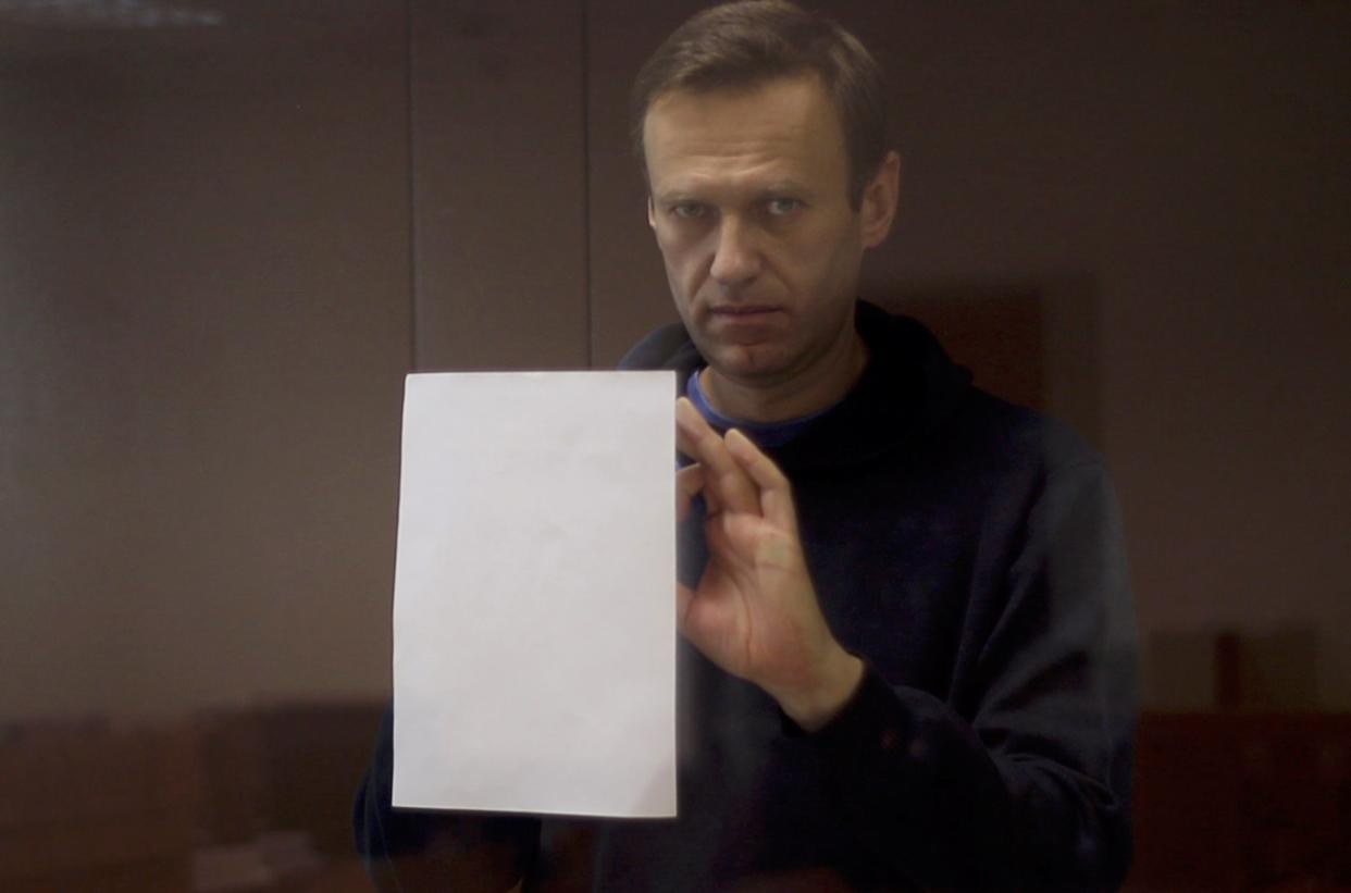 Kremlin critic Alexei Navalny, who is accused of slandering a Russian World War Two veteran, is seen inside a defendant dock during a court hearing in Moscow (via REUTERS)