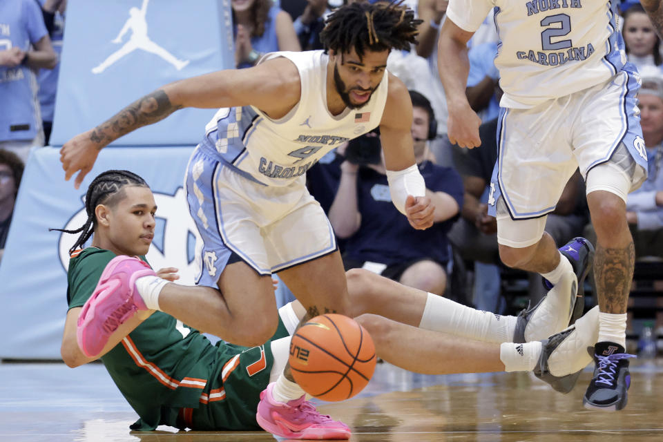 North Carolina guard RJ Davis (4) Miami guard Kyshawn George, bottom, go for the ball during the first half of an NCAA college basketball game Monday, Feb. 26, 2024, in Chapel Hill, N.C. (AP Photo/Chris Seward)