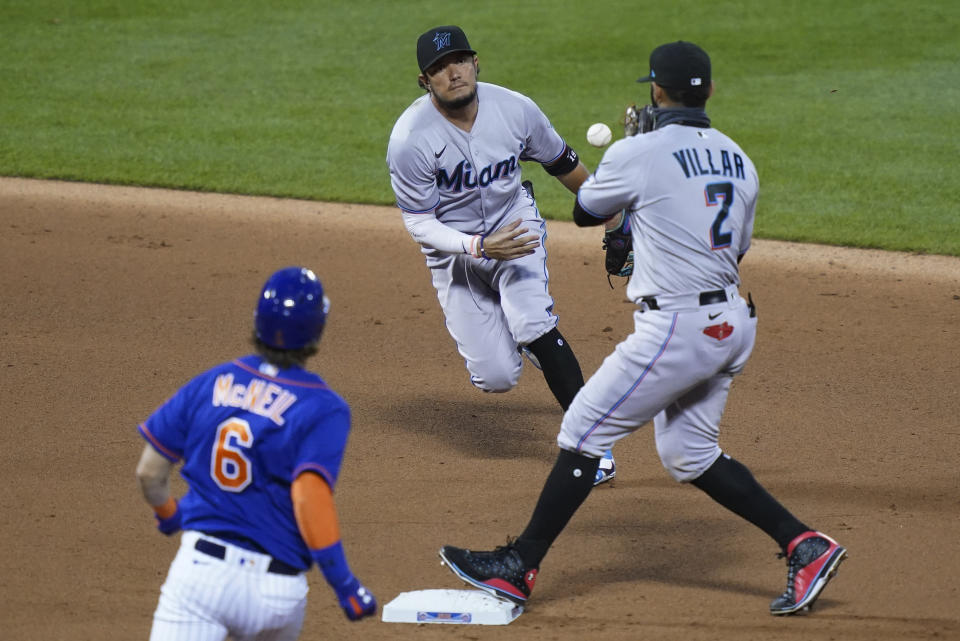 Miami Marlins shortstop Miguel Rojas, center, flips the ball to second baseman Jonathan Villar to force out New York Mets' Jeff McNeil (6) during the fifth inning in the first baseball game of a doubleheader, Tuesday, Aug. 25, 2020, in New York. (AP Photo/John Minchillo)