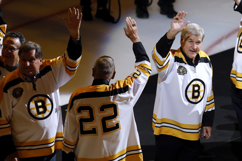 Former Boston Bruin Bobby Orr, right, waves while taking part in a banner-raising ceremony as part of the team's season-long centennial celebrations, before the Bruins' NHL hockey game against the Montreal Canadiens, Saturday, Nov. 18, 2023, in Boston. (AP Photo/Michael Dwyer)