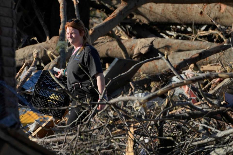 A Rolling Fork, Miss., resident walks through fallen trees as she attempts to salvage personal items following a tornado the night before that heavily damaged the Mississippi Delta community, Saturday, March 25, 2023. (AP Photo/Rogelio V. Solis)