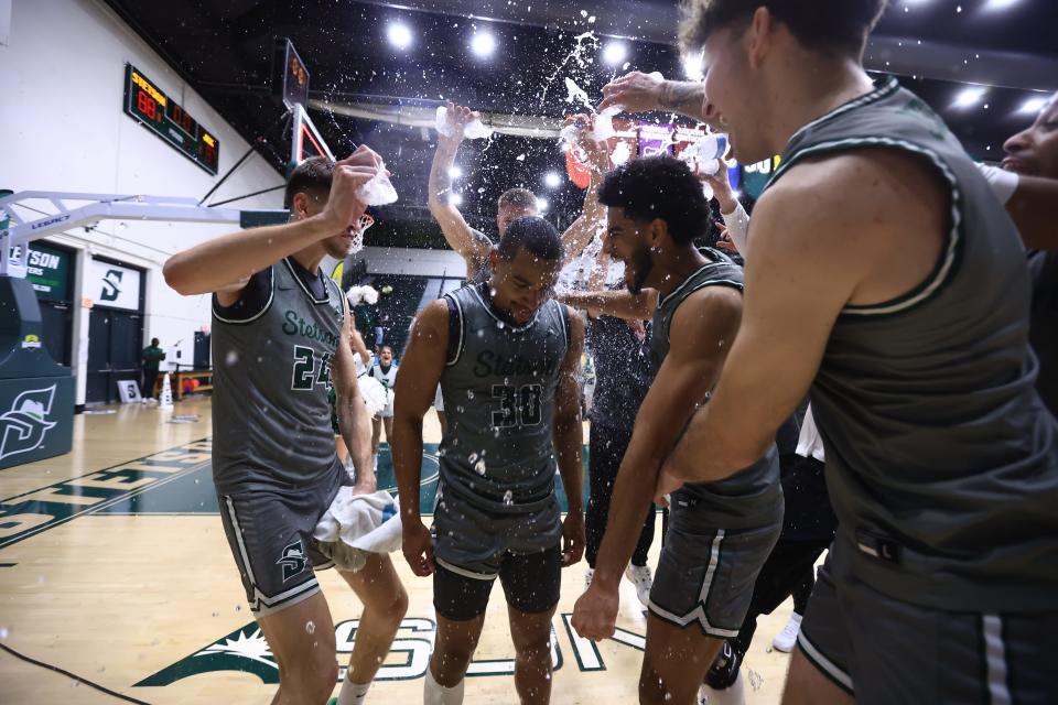 Stetson point guard Stephan Swenson (30) is mobbed by teammates after the Hatters earned a thrilling 88-87 win over Jacksonville in an ASUN semifinal on Thursday, March 7, 2024 in DeLand.