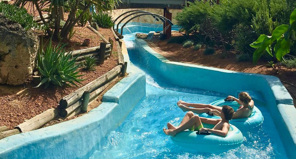 Two people in tyres go down a waterslide at Adventure World in Perth.