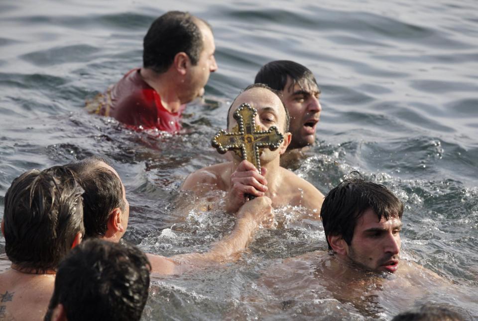 Greek Orthodox faithful hold a wooden crucifix as they swim in the Golden Horn in Istanbul January 6, 2014. Greek Orthodox faithful swam to retrieve the wooden crucifix thrown into the Golden Horn in Bosphorus during Epiphany Day celebrations. REUTERS/Osman Orsal (TURKEY - Tags: RELIGION SOCIETY)