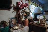Un par de cruces junto con una veladora y flores se despliegan en un pequeño altar dedicado a los padres de José Juan Serralde que murieron en mayo de COVID-19, en el cuarto donde vivían en San Gregorio Atlapulco, Xochimilco, en Ciudad de México, el miércoles 29 de julio de 2020. (AP Foto/Rebecca Blackwell)