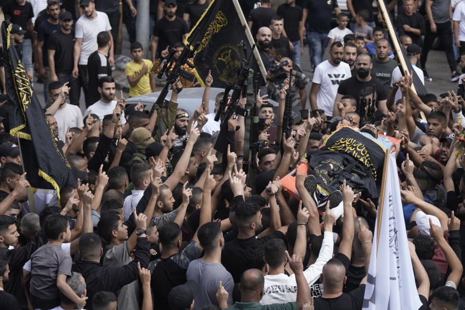 Mourners carry the body of Matin Dababa, draped in the flag of the Islamic Jihad militant group, at his funeral in the Jenin refugee camp, Friday, Oct. 14, 2022. The Palestinian Health Ministry says the Israeli military shot and killed two Palestinians, including Dababa, during a raid into the Jenin refugee camp in the occupied West Bank. (AP Photo/Majdi Mohammed)