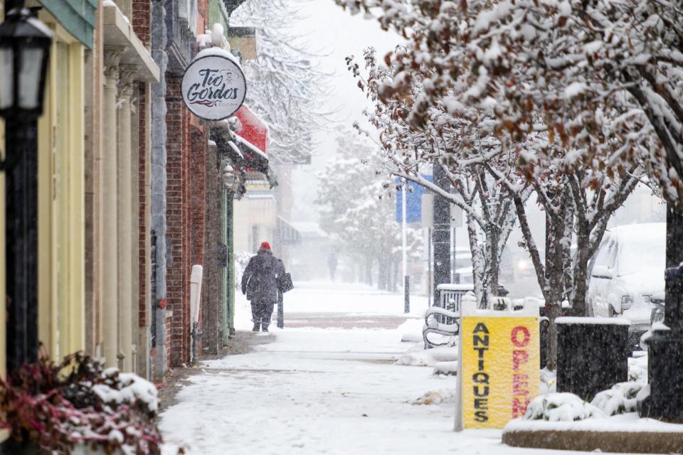 A person waits in the snow to cross McMorran Boulevard Monday, Nov. 11, 2019, in downtown Port Huron. The National Weather Service has issued a winter storm warning for the area, effective until Tuesday morning.