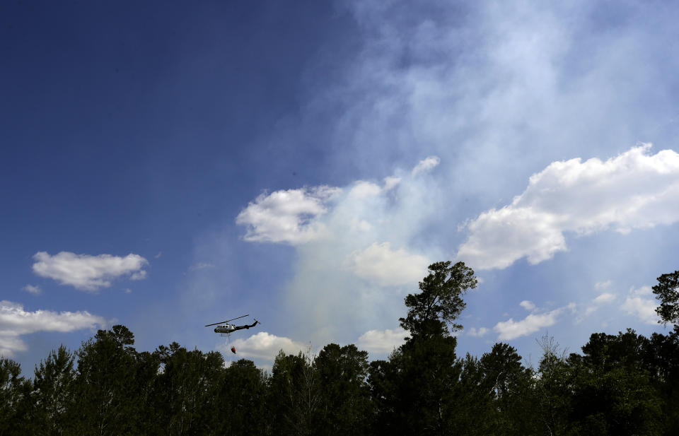 A Florida Division of Forestry helicopter drops a bucket of water on a wildfire Tuesday, April 11, 2017, in Hudson, Fla. Florida Gov. Rick Scott has declared a state of emergency as more than 100 wildfires actively burn statewide. (AP Photo/Chris O'Meara)