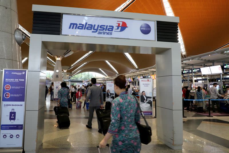 FILE PHOTO: Malaysia Airlines crew members walk under a Malaysia Airlines arch at Kuala Lumpur International Airport in Sepang